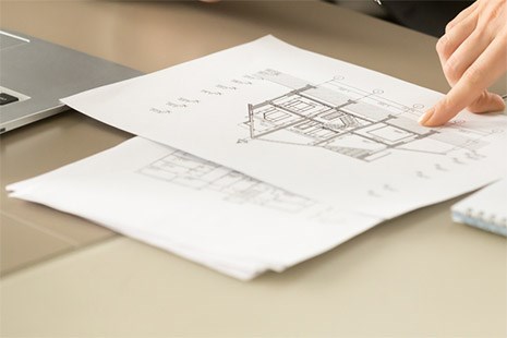 Blueprints for a roofing project being reviewed by a professional at Coastal Roofing Experts.