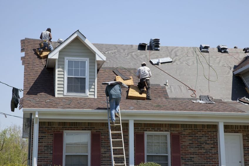 Professional roofers from Coastal Roofing Experts installing a durable asphalt shingle roof on a brick home in Southeastern North Carolina.