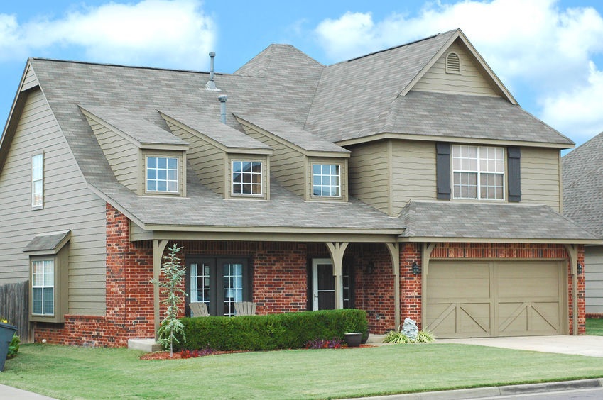 A beautifully installed asphalt shingle roof on a two-story brick and siding home by Coastal Roofing Experts.