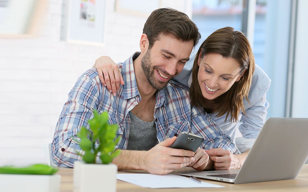 A happy couple reviewing their roofing project estimate online with Coastal Roofing Experts.